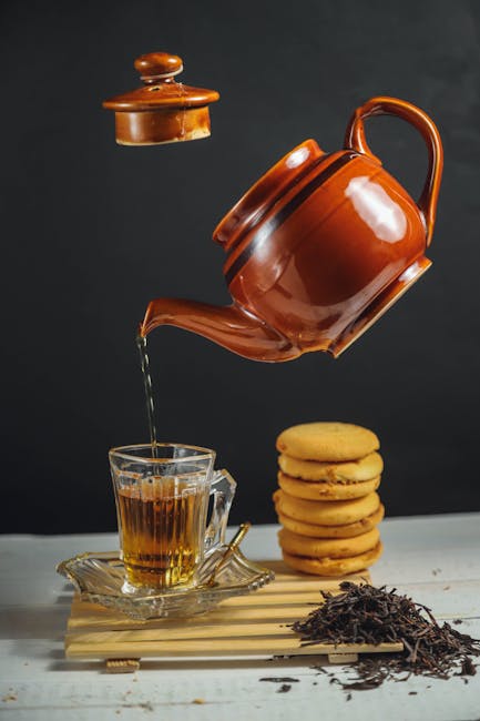 Food Aesthetics - Floating brown teapot pouring tea into glass cup #11333375