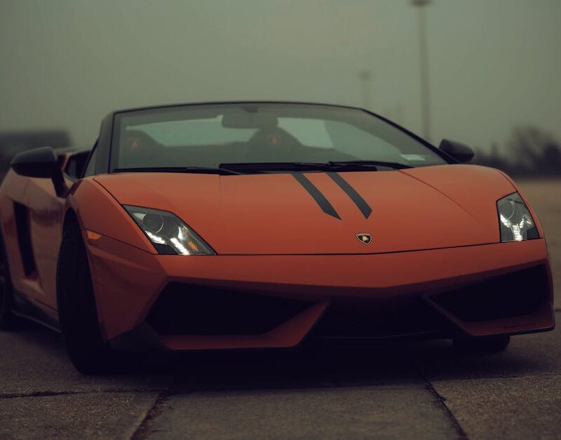 Luxury Cars - A matte orange Lamborghini parked on a cloudy da #13155785